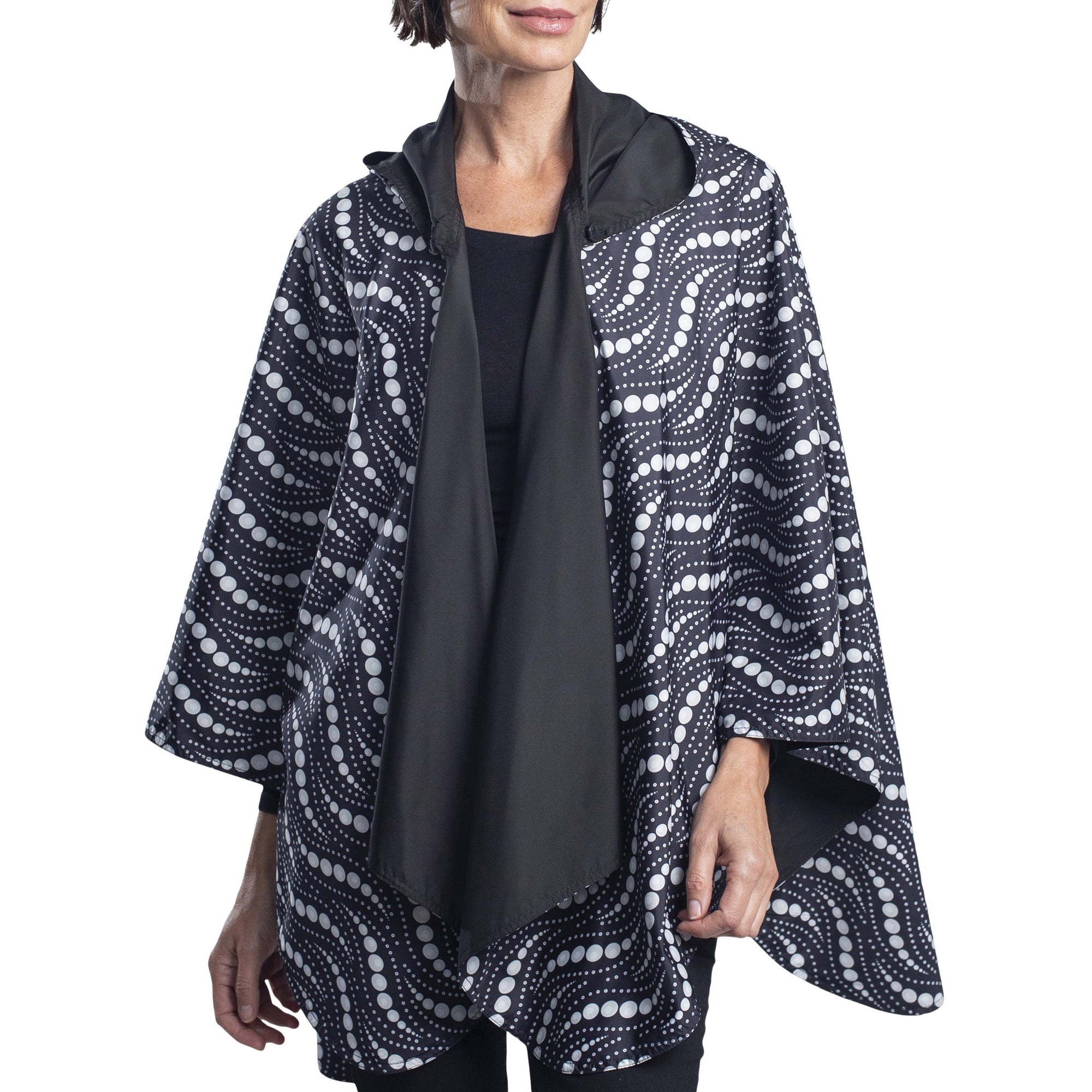 Women wearing a Black/Wavy Pearls Reversible RainCaper travel cape with the Black side out, revealing the Wavy Pearls print at the lapels and cuffs